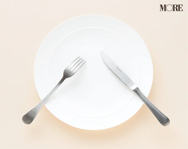 マナーブック冠婚葬祭食事編　【基本のテーブルマナー】和食・洋食の正しい振る舞いを解説。ナプキンを膝にかけている女性の写真。食事中のカトラリーの置き方