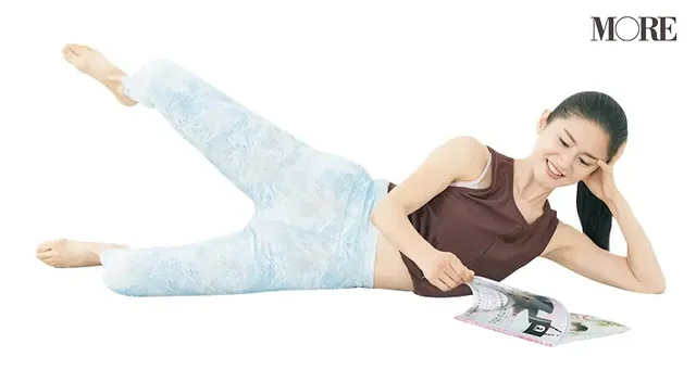 雑誌を読みながらストレッチする女性