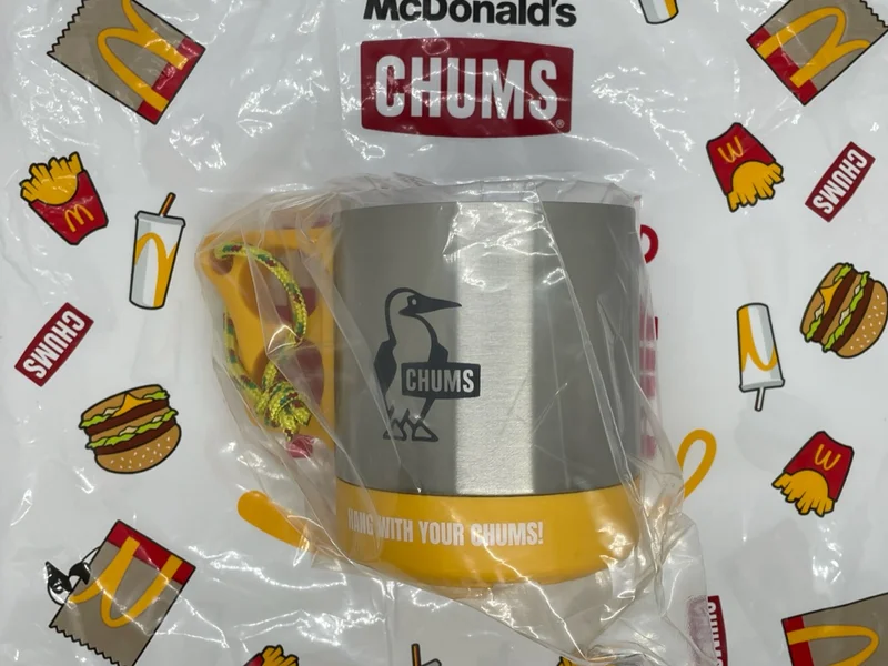 黄色い持ち手で、ステンレスのマグカップにはCHUMSのロゴが描いてある。