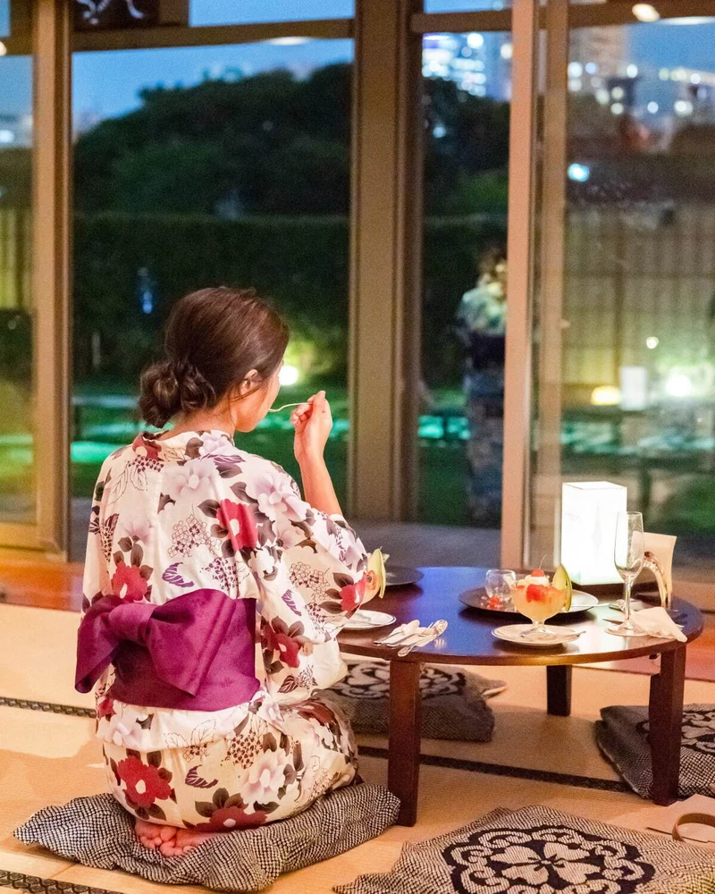 縁側から東京タワーを眺めている浴衣の女性