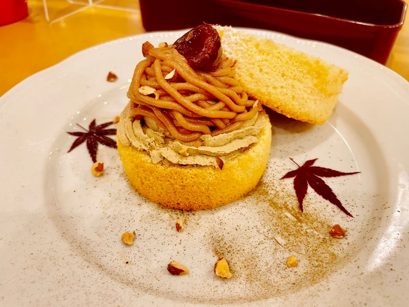 丸いシフォンケーキの上に茶色いモンブランと栗が乗ったデザートプレート。横にはもう一枚丸いシフォンケーキが添えられている