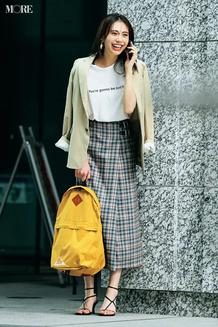 【通勤リュックコーデ】Tシャツ×チェック柄スカート×ジャケットのコーデにリュックを持った女性