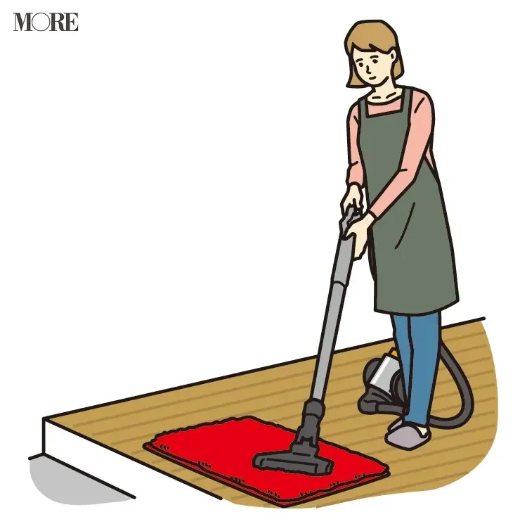 風水の開運掃除法で玄関マットに掃除機をかける女性