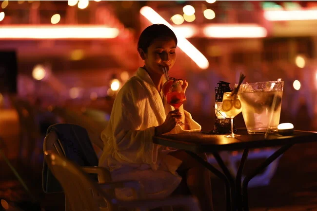 「NAKED NIGHT SAUNA HOTEL NEW OTANI -CITY RETREAT-」の夜の部で、プールサイドにてドリンクを飲んでいる女性