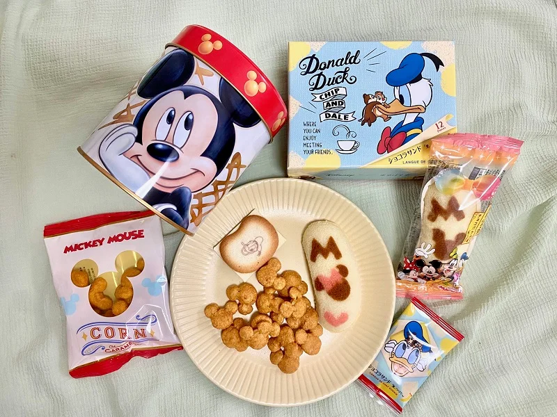 「Disney SWEETS COLLECTION by 東京ばな奈」のお菓子3種類（「ミッキーマウス/コーン キャラメル味」、「ミッキー＆フレンズ/東京ばな奈『⾒ぃつけたっ』」、「ドナルドダック、チップ＆デール/ショコラサンド『⾒ぃつけたっ』」）が並んだ様子
