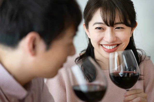 男性とデート中、ワイングラスを手に持っている女性