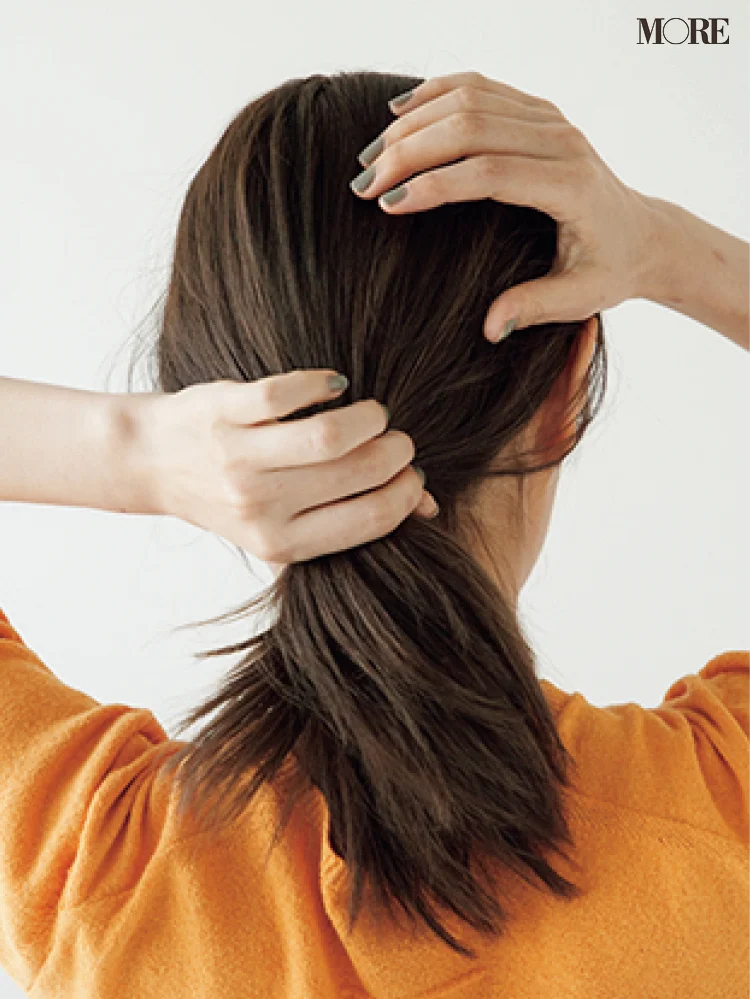 梅雨の低めおだんごヘアアレンジで髪にワックスをつける女性