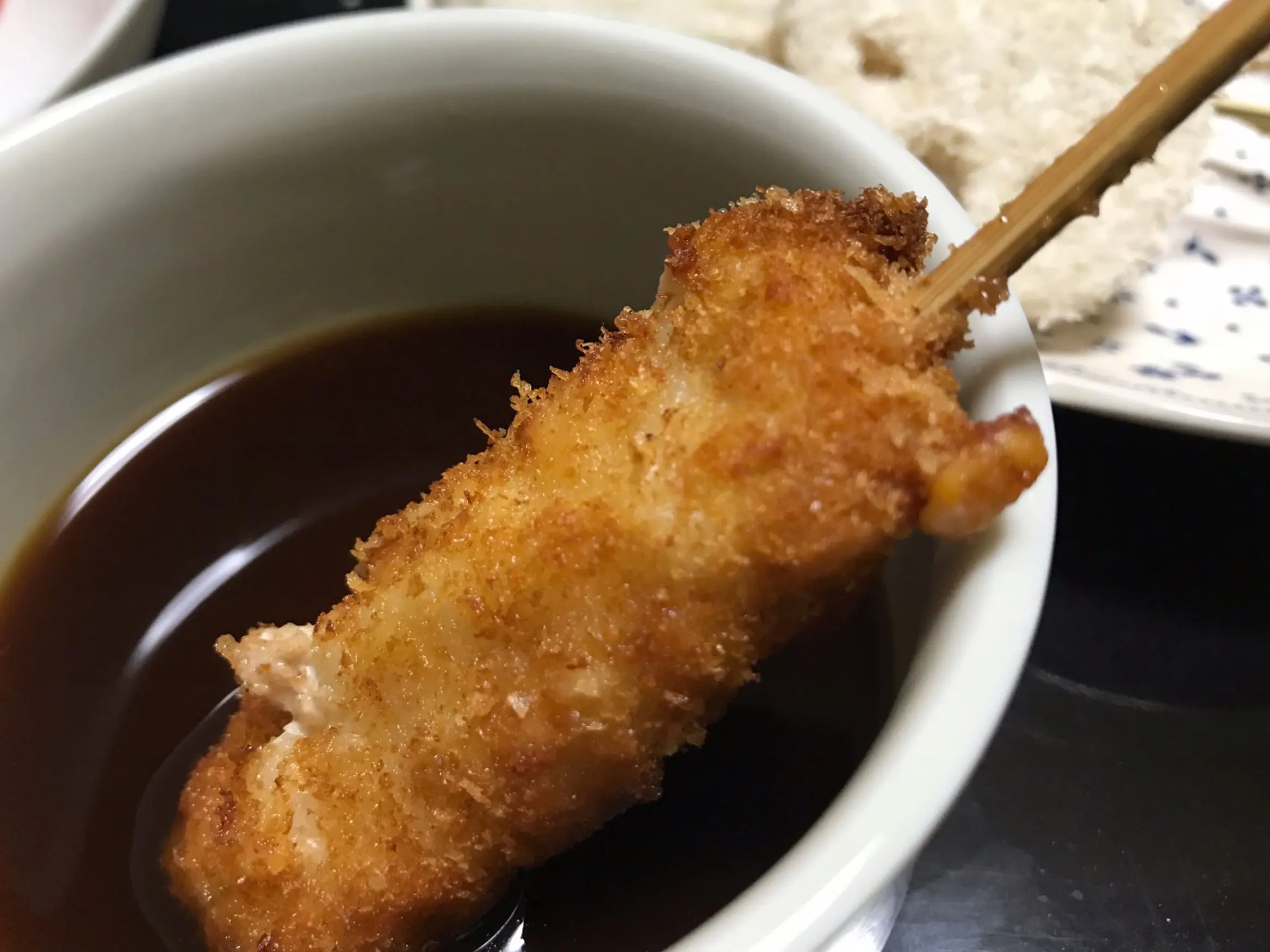 串カツにソースをつけているところ