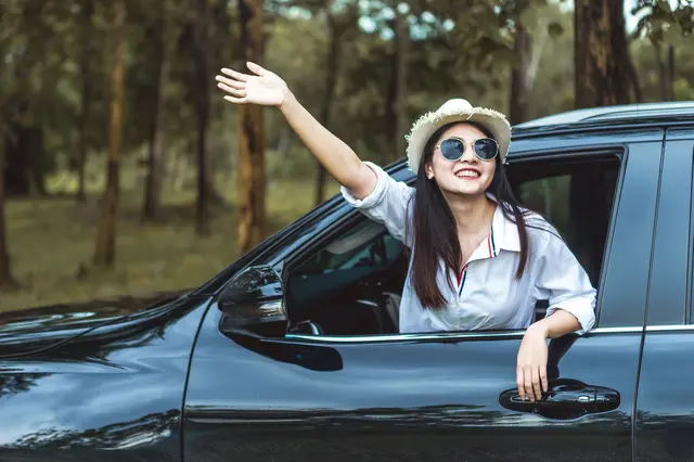車の助手席から外に向かって手を振る女性