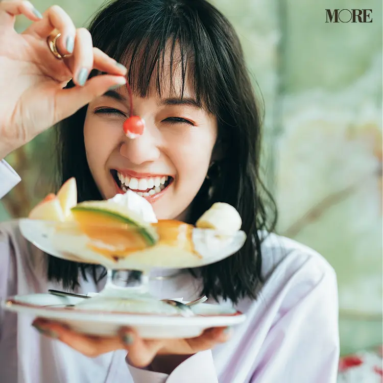 ピンクのバンドカラーシャツを着てさくらんぼを持った佐藤栞里