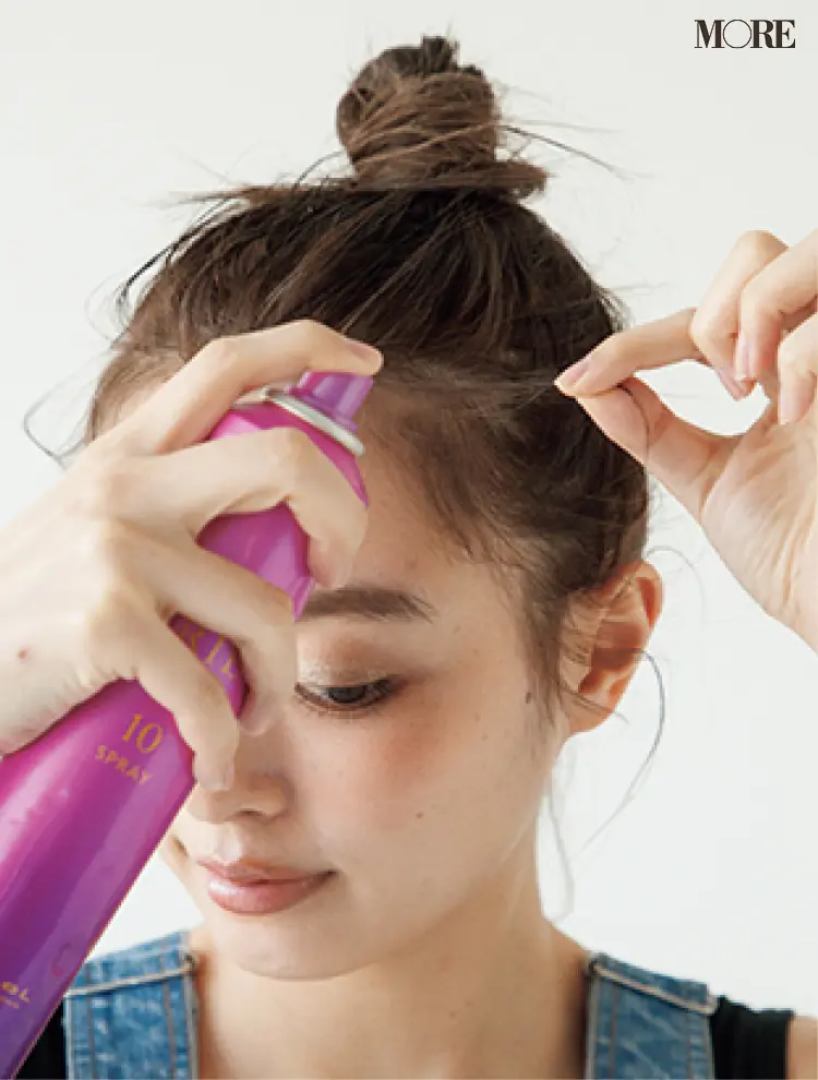 梅雨のおだんごヘアアレンジでスプレーを髪にかける女性