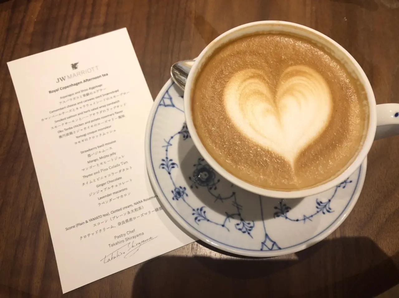 アフタヌーンティーのメニューとカフェラテが入っているティーカップ