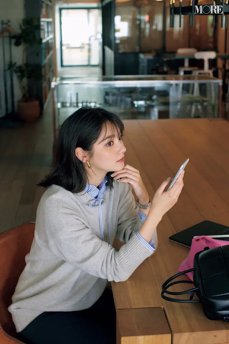 ストライプ柄シャツとグレージュニットをレイヤードした新川優愛