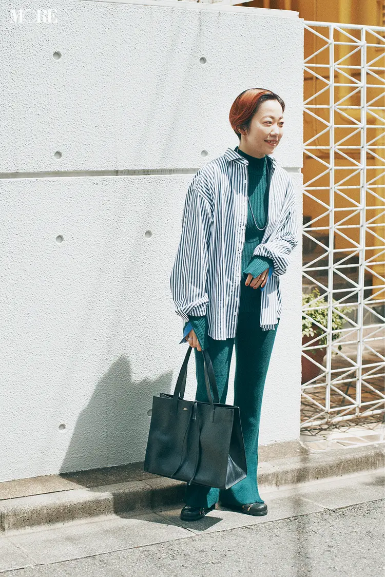 ニットセットアップにストライプシャツをはおった高野麻子さん