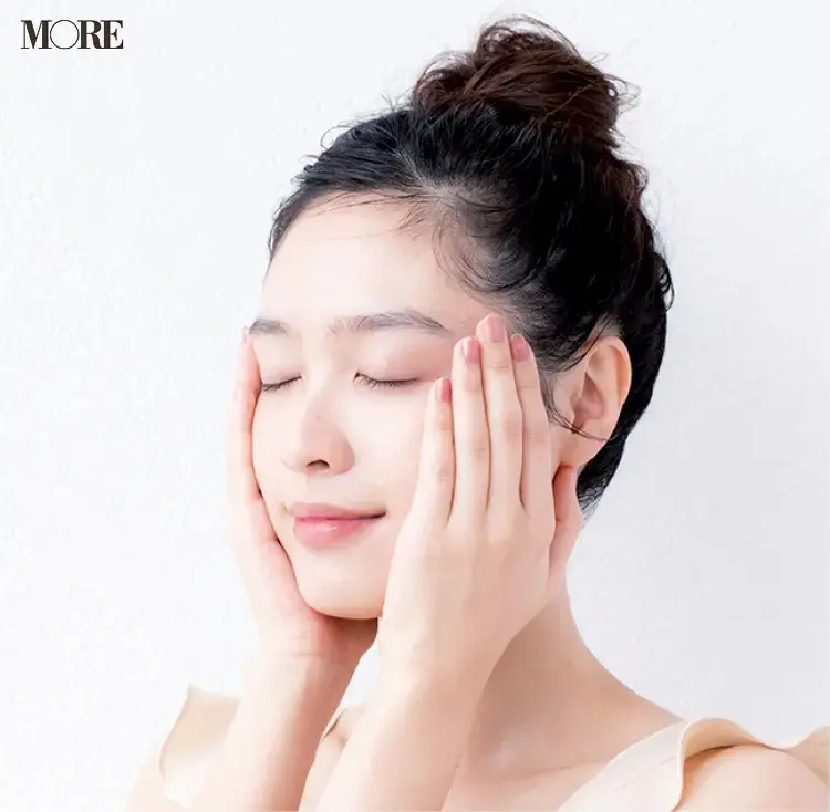 乳液を両手で顔に塗る女性