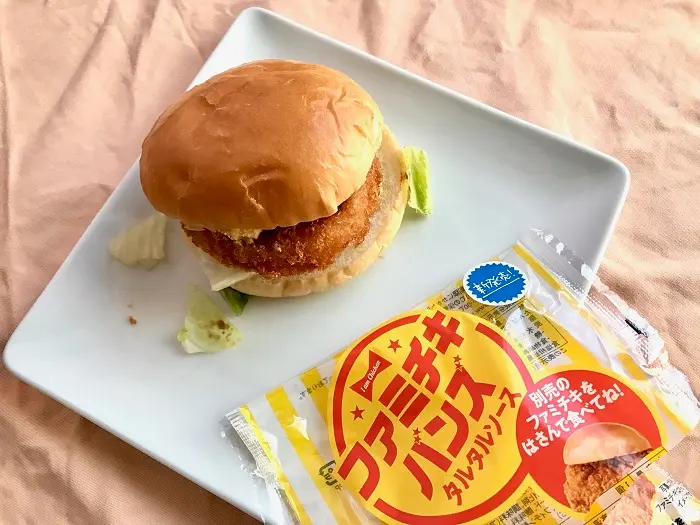 『ファミリーマート』の商品「ファミチキバンズ（タルタルソース）」に、「北海道グラタンコロッケ」、「こだわりマヨネーズのたまごサラダ」、「レタスミックスサラダ」を挟んで、パッケージの横に並べた写真