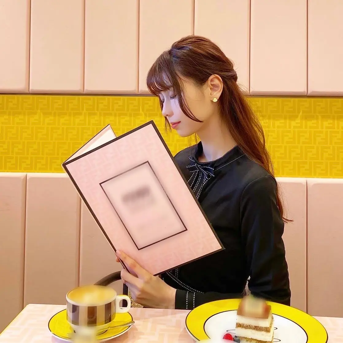 カフェでピンク色のメニューを見ている目を閉じた女性