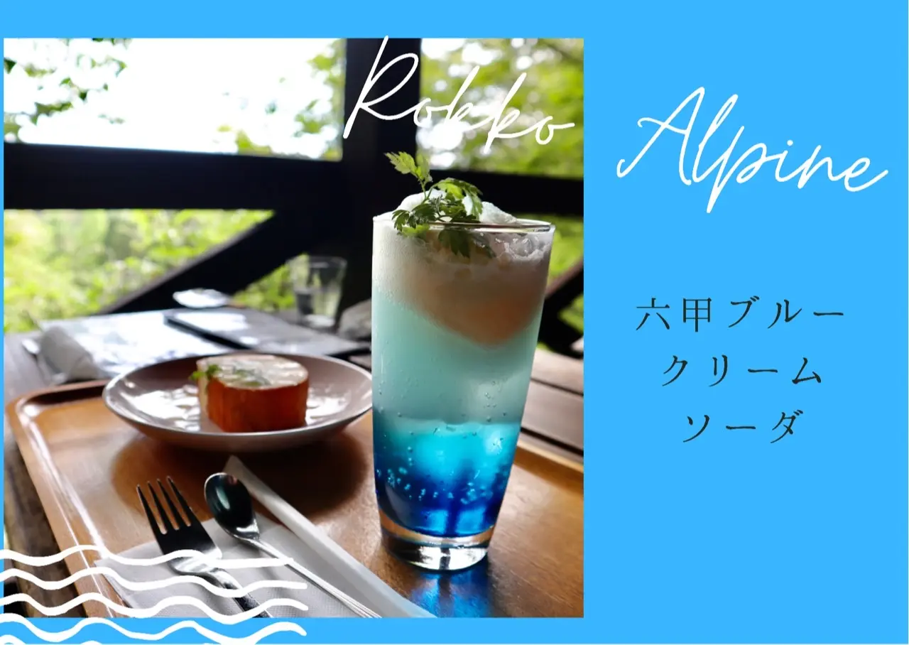 鮮やかな青色のソーダの上にバニラアイスが乗ったクリームソーダ。その後ろにロールケーキ。森の中にあるカフェで撮影