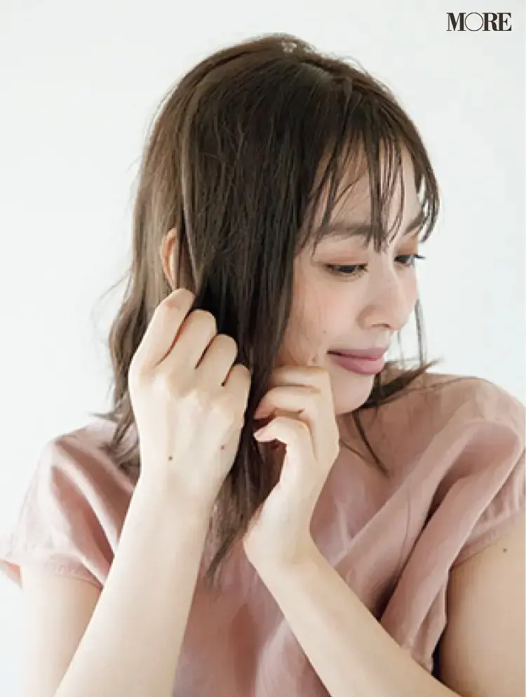 梅雨の三つ編みヘアアレンジでヘアワックスを髪になじませる女性