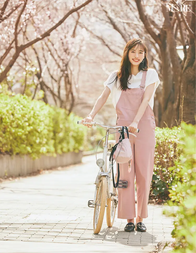 ピンクのサロペットを着て自転車を押す井桁弘恵