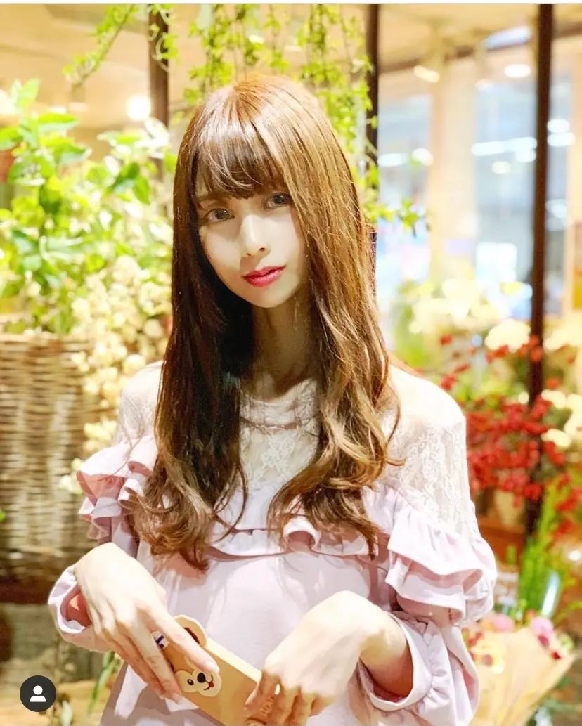 花屋の前に立つ携帯を持った髪の長い女性