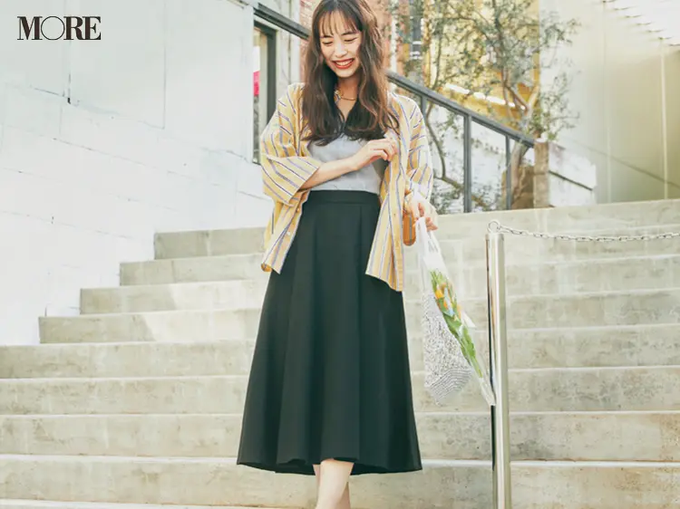 黄色のシャツ×黒のフレアスカートコーデで花を持った井桁弘恵