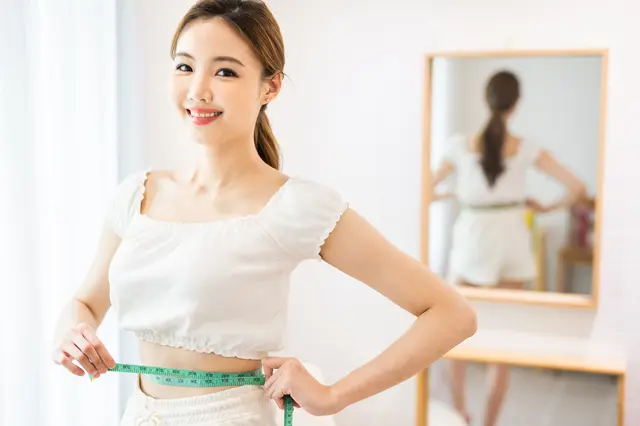 女性がメジャーでウエストを図っている様子